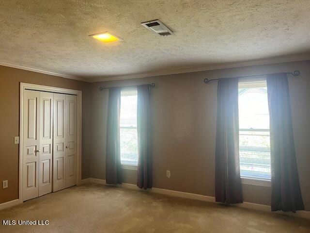 unfurnished bedroom with a closet, a textured ceiling, carpet, and crown molding