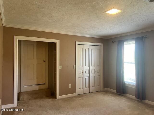 unfurnished bedroom with a textured ceiling, ornamental molding, and light colored carpet