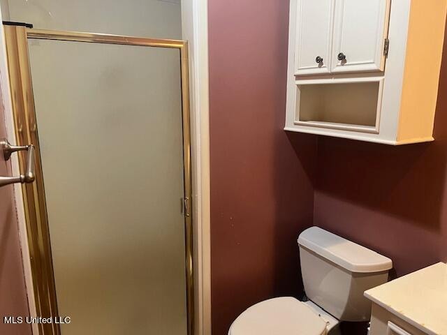 bathroom with vanity, a shower with shower door, and toilet