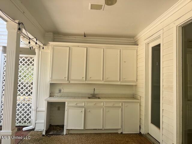 kitchen featuring white cabinetry, crown molding, sink, and plenty of natural light