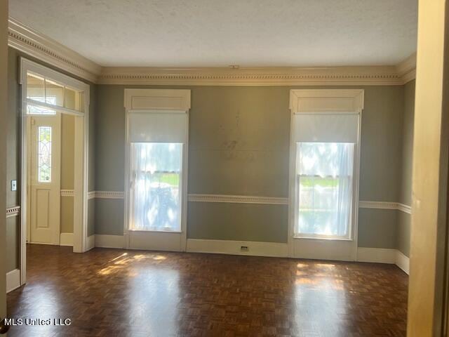 spare room with crown molding, dark parquet floors, and a textured ceiling