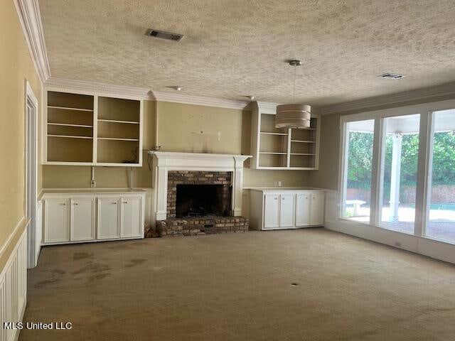 unfurnished living room featuring ornamental molding, a textured ceiling, carpet flooring, and a brick fireplace