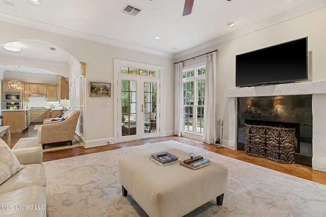 living room featuring french doors, light hardwood / wood-style floors, crown molding, and ceiling fan