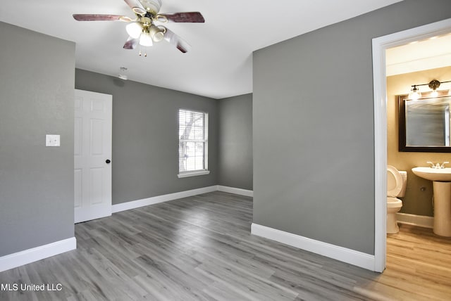 spare room with light wood-type flooring, a sink, baseboards, and a ceiling fan