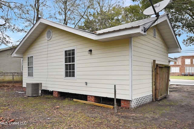 view of home's exterior with fence, metal roof, and central AC