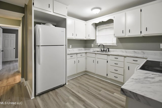 kitchen featuring light countertops, a sink, freestanding refrigerator, and white cabinets