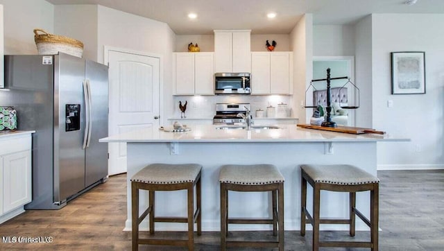 kitchen featuring white cabinets, a kitchen island with sink, and appliances with stainless steel finishes