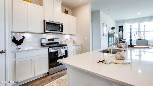 kitchen featuring decorative backsplash, sink, white cabinetry, light stone countertops, and appliances with stainless steel finishes