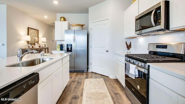 kitchen featuring sink, light hardwood / wood-style flooring, light stone countertops, stainless steel appliances, and white cabinets