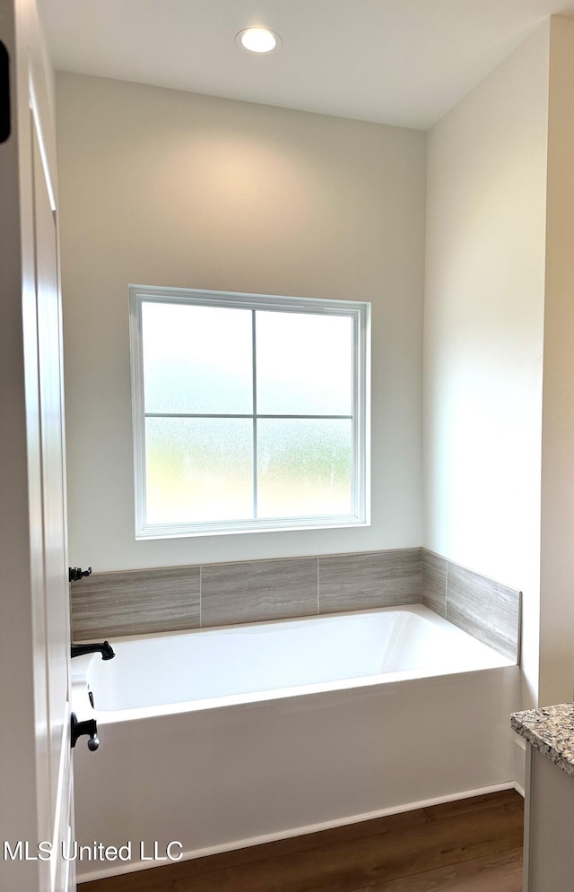 bathroom featuring vanity, hardwood / wood-style floors, and a washtub