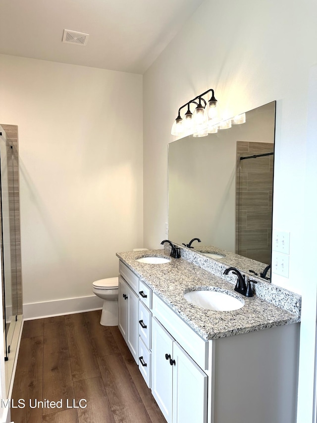 bathroom featuring a shower with door, vanity, hardwood / wood-style flooring, and toilet