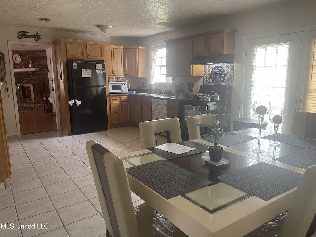 kitchen with light tile patterned floors, a textured ceiling, freestanding refrigerator, visible vents, and a sink