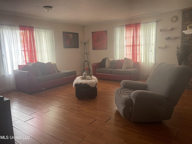 living room featuring a textured ceiling, wood finished floors, crown molding, and a wealth of natural light
