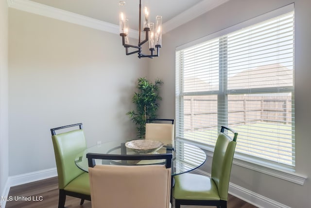 dining room with baseboards, ornamental molding, wood finished floors, and a notable chandelier