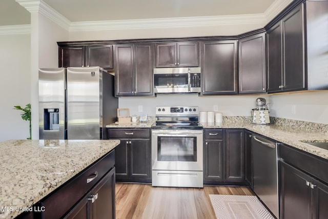 kitchen with dark brown cabinetry, light stone countertops, stainless steel appliances, light wood-type flooring, and ornamental molding