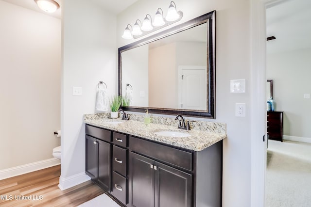 bathroom with double vanity, a sink, baseboards, and toilet