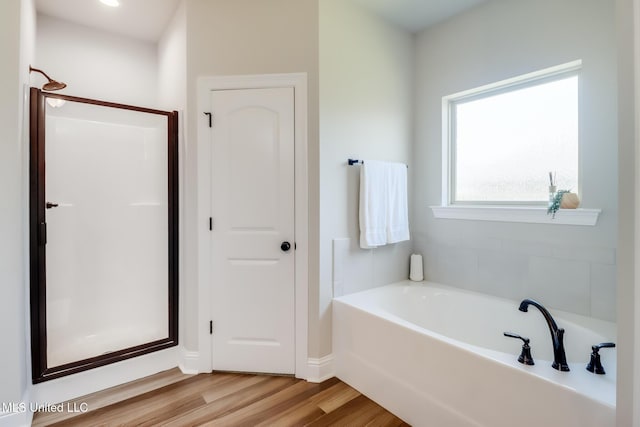full bathroom featuring baseboards, a shower stall, wood finished floors, and a garden tub