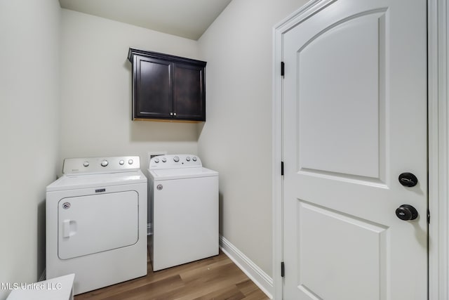 laundry area with wood finished floors, baseboards, cabinet space, and washing machine and clothes dryer