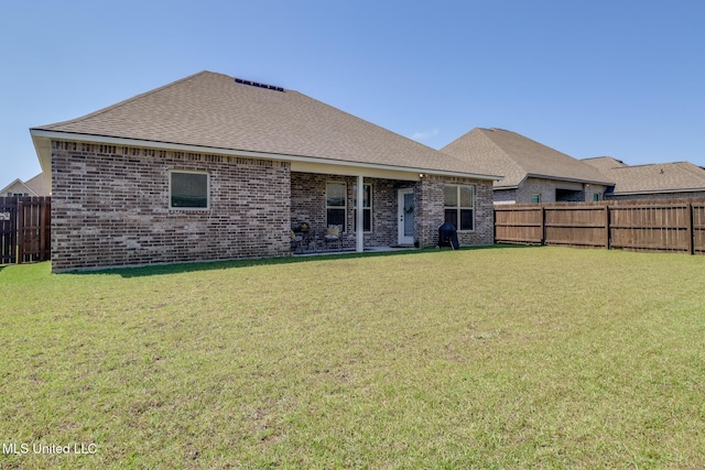 back of property with brick siding, a fenced backyard, a yard, and a shingled roof
