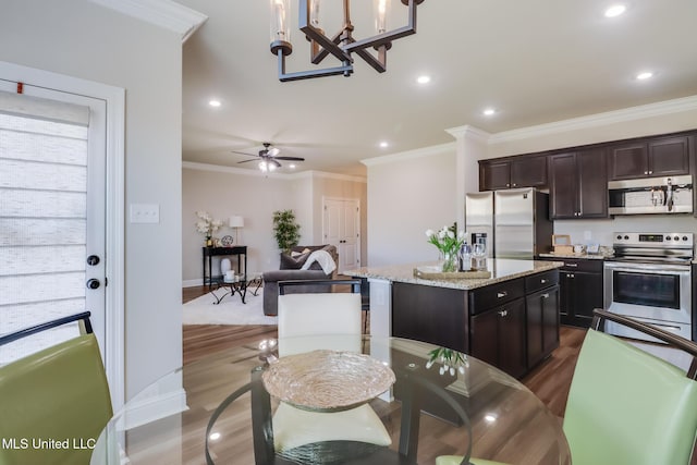 kitchen featuring crown molding, appliances with stainless steel finishes, a center island, and dark wood-type flooring