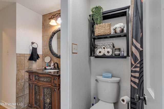 bathroom with vanity, toilet, and tile walls