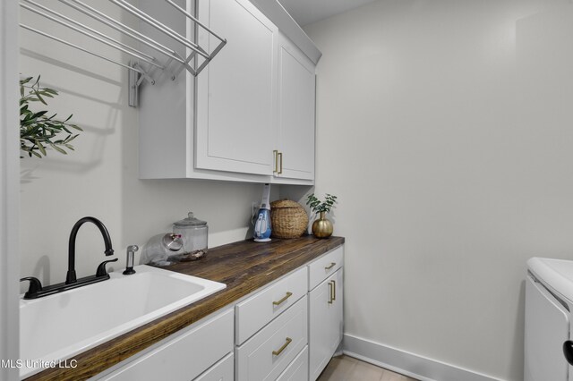 212 Ashbury Cv, Canton, MS 39046 - washroom featuring cabinet space, baseboards, washing machine and dryer, and a sink