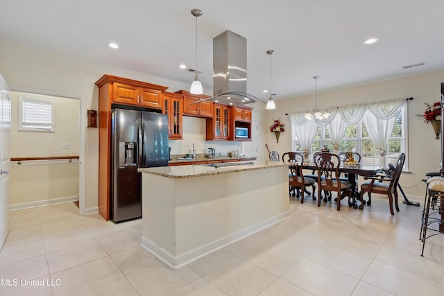 kitchen with sink, pendant lighting, light stone counters, an inviting chandelier, and stainless steel refrigerator with ice dispenser