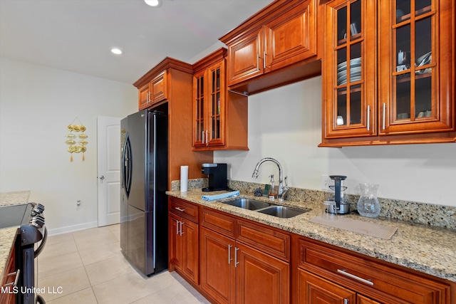 kitchen featuring fridge, sink, light tile patterned flooring, range, and light stone counters