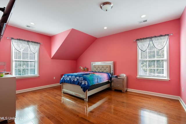 bedroom with hardwood / wood-style flooring, lofted ceiling, and multiple windows