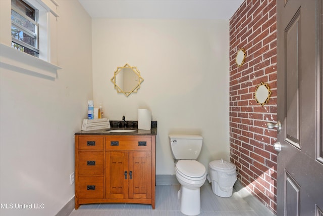 bathroom featuring vanity, toilet, brick wall, and tile patterned floors