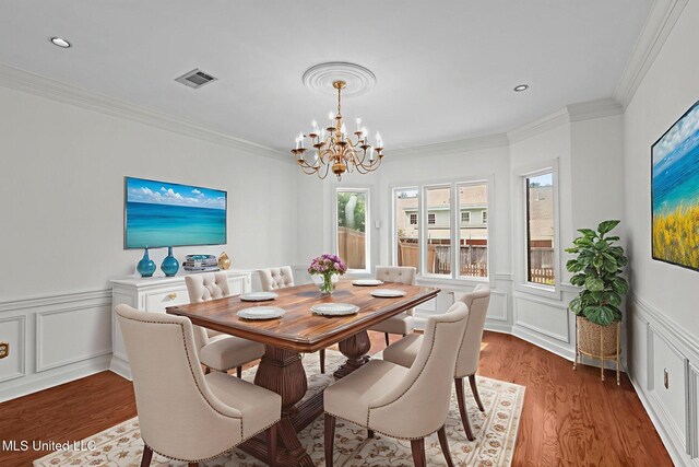 316 Meadow Creek Pl, Jackson, MS 39211 - dining area featuring a chandelier, wood finished floors, a decorative wall, crown molding, and a wainscoted wall