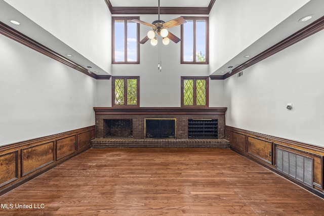 316 Meadow Creek Pl, Jackson, MS 39211 - unfurnished living room with wainscoting, a towering ceiling, a brick fireplace, ceiling fan, and crown molding