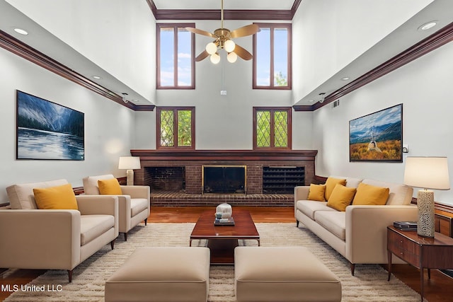 316 Meadow Creek Pl, Jackson, MS 39211 - living room featuring a towering ceiling, wood finished floors, ceiling fan, a brick fireplace, and ornamental molding