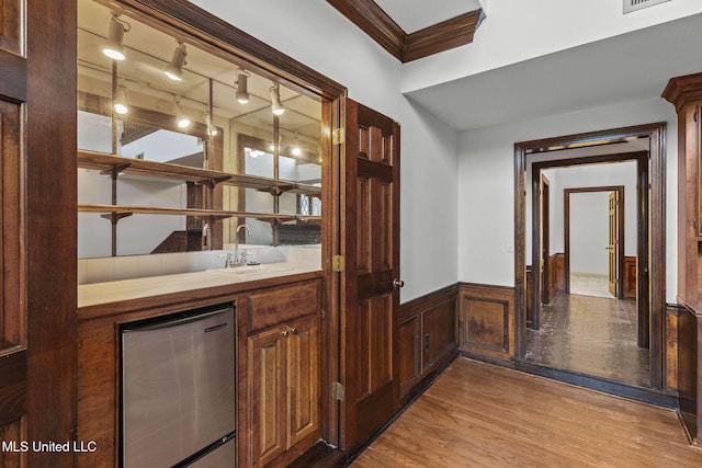 316 Meadow Creek Pl, Jackson, MS 39211 - indoor wet bar featuring refrigerator, a wainscoted wall, light wood-style flooring, crown molding, and rail lighting
