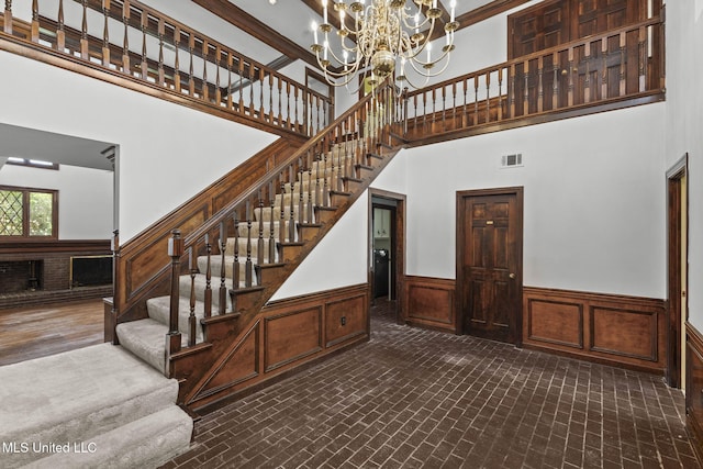 316 Meadow Creek Pl, Jackson, MS 39211 - stairway featuring a towering ceiling, a chandelier, wainscoting, and brick patterned floors