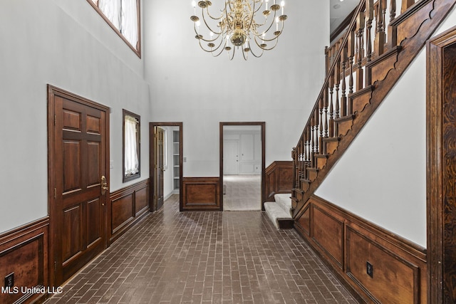 316 Meadow Creek Pl, Jackson, MS 39211 - entryway with a chandelier, stairs, wainscoting, a towering ceiling, and brick patterned flooring