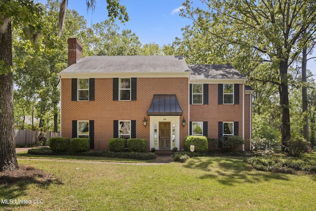 39 Moss Forest Cir, Jackson, MS 39211 - colonial home featuring a chimney, brick siding, fence, a shingled roof, and a front lawn