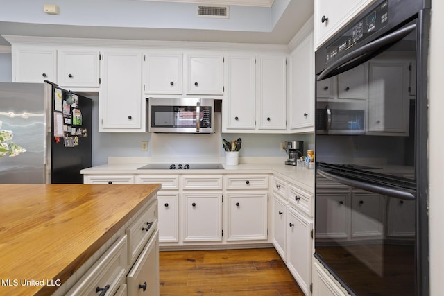 39 Moss Forest Cir, Jackson, MS 39211 - kitchen with visible vents, black appliances, wood finished floors, and white cabinets