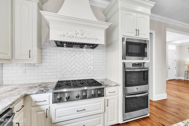 413 Miles Cv, Brandon, MS 39047 - kitchen with stainless steel appliances, custom range hood, backsplash, ornamental molding, and light wood-style flooring