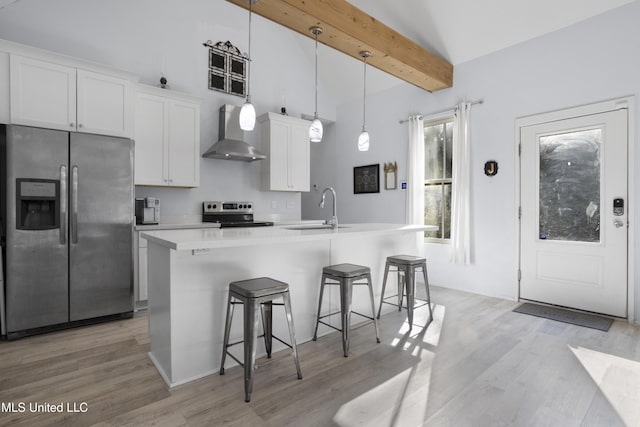 kitchen featuring a kitchen island with sink, wall chimney exhaust hood, a sink, light wood finished floors, and stainless steel appliances
