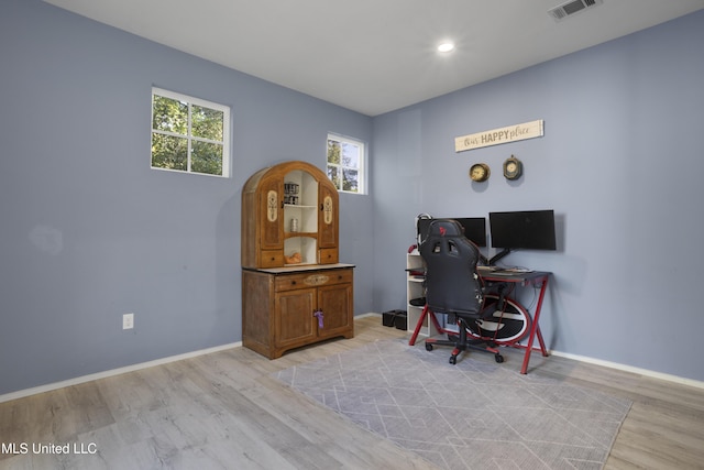 office area with baseboards, plenty of natural light, light wood-type flooring, and visible vents