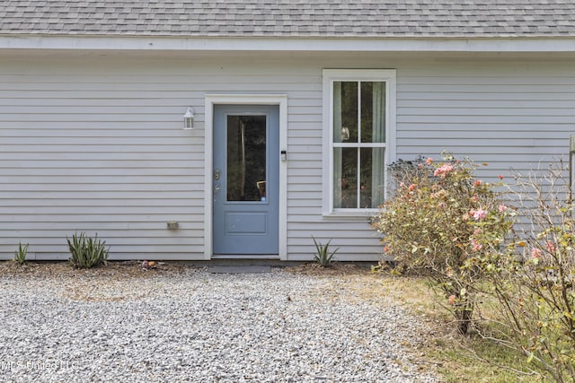 doorway to property with roof with shingles
