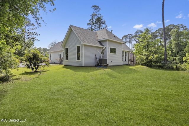 back of property with a lawn and a shingled roof