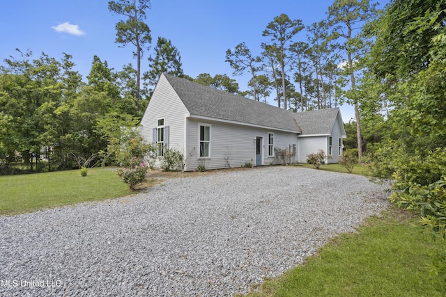 exterior space featuring roof with shingles, a yard, and driveway
