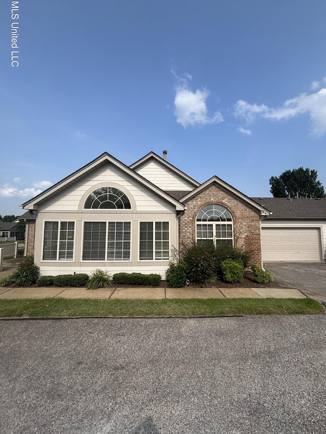 8911 Oak Branch Ln, Olive Branch, MS 38654 - view of home's exterior with brick siding, an attached garage, and asphalt driveway