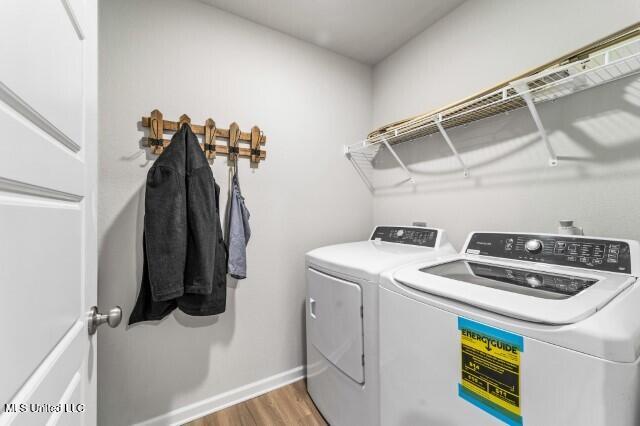 washroom featuring washer and clothes dryer, wood finished floors, and baseboards