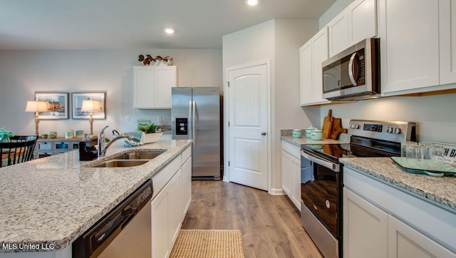 kitchen featuring stainless steel appliances, a sink, recessed lighting, white cabinets, and light wood-style flooring