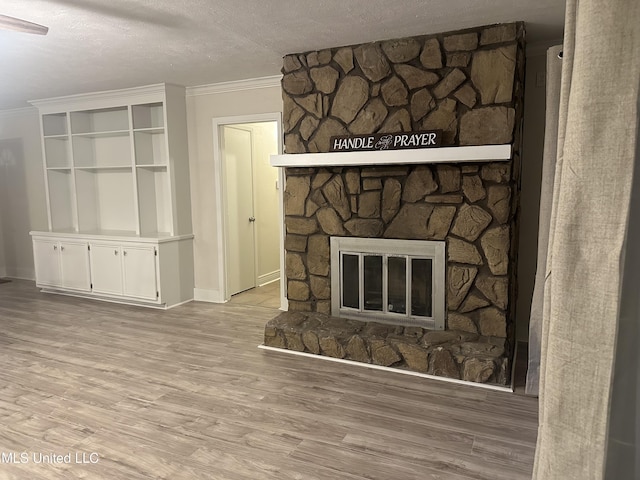 interior details with crown molding, a stone fireplace, wood-type flooring, and a textured ceiling