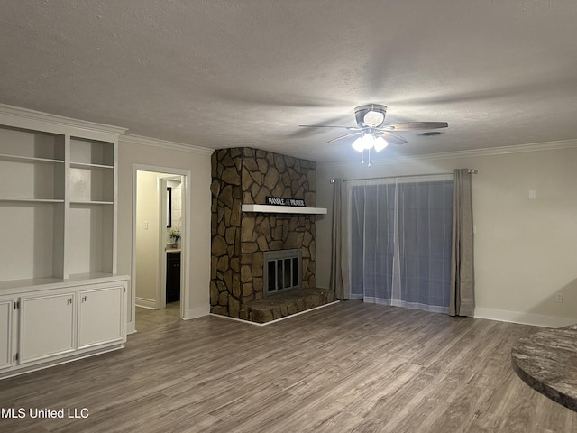 unfurnished living room with ornamental molding, a textured ceiling, a fireplace, and light hardwood / wood-style floors