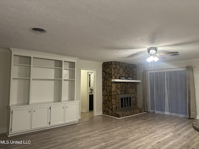 unfurnished living room featuring ornamental molding, a fireplace, light hardwood / wood-style floors, and a textured ceiling